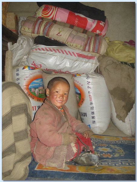 Butti Gurung sitzt vor Saecken mit Waren aus Tibet.JPG