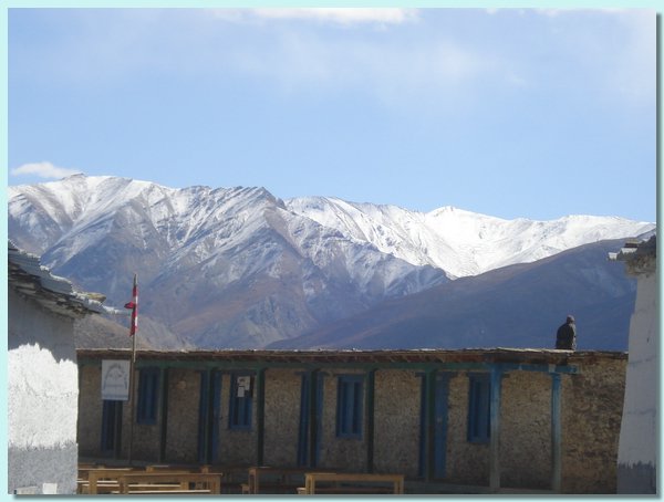 Ein alter Mann auf einem Schulhaus, auf den Bergen hat es geschneit.JPG